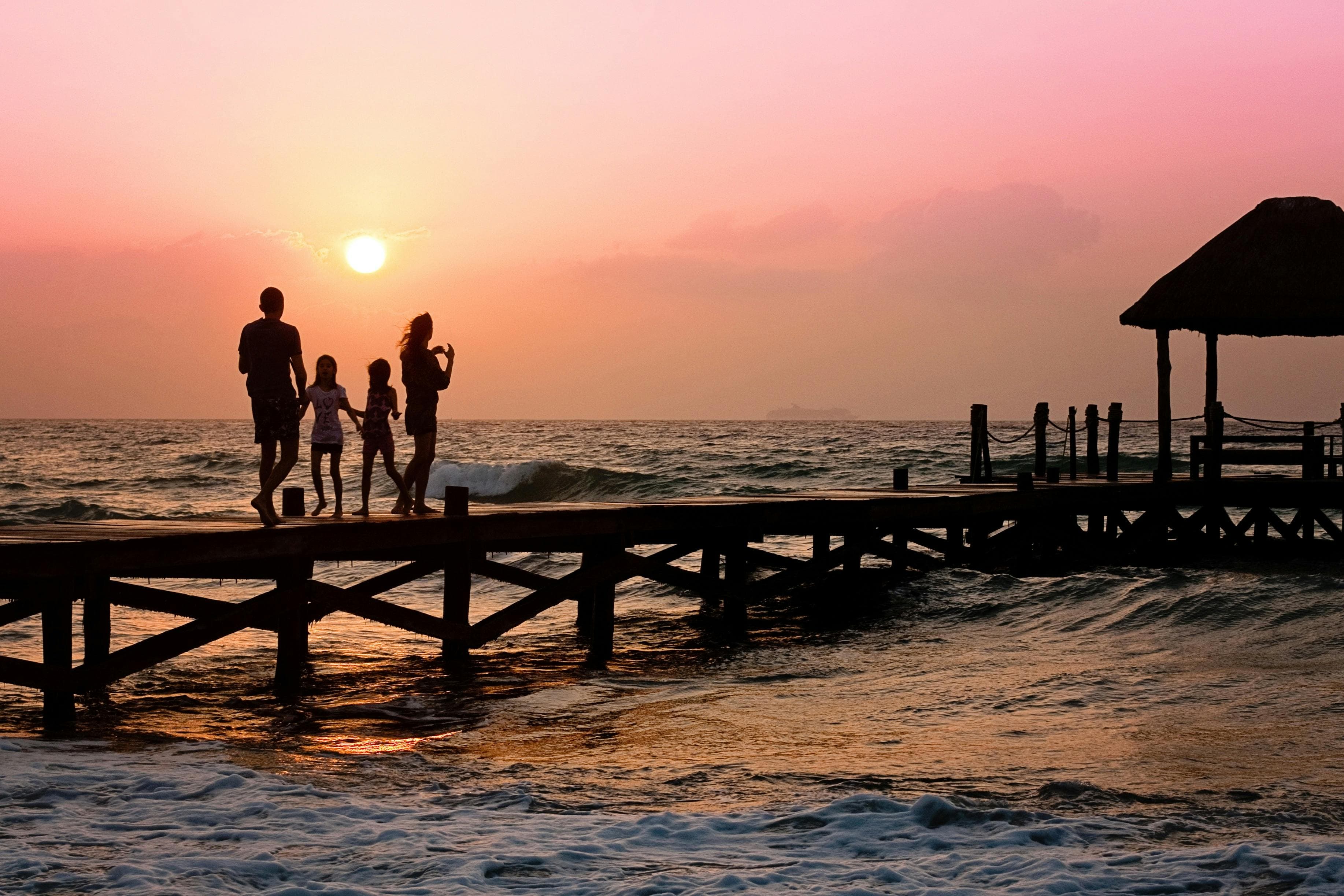 A family of four on a pier at sunset